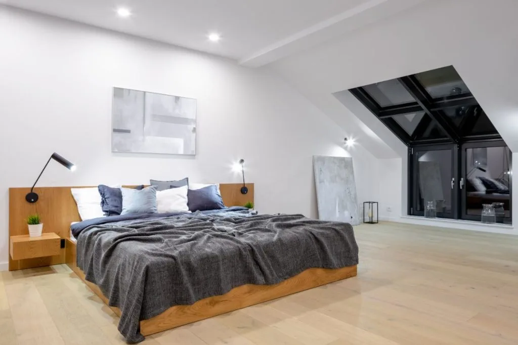 Mansard loft conversion bedroom with Juliet balcony, minimal design, and wood- effect linoleum flooring -London renovation